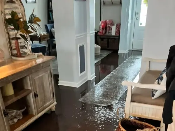 Water spread across a hardwood hallway floor after a leak