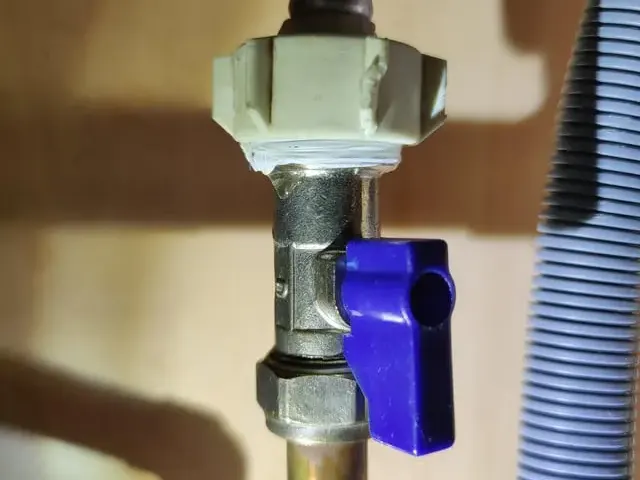 Washing machine supply valve and drain hose behind a laundry appliance