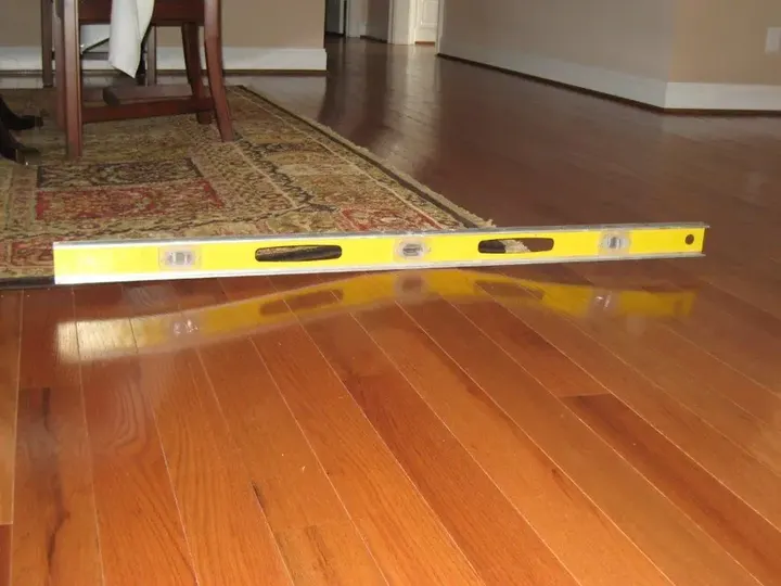 Level laid across cupped hardwood flooring after water damage